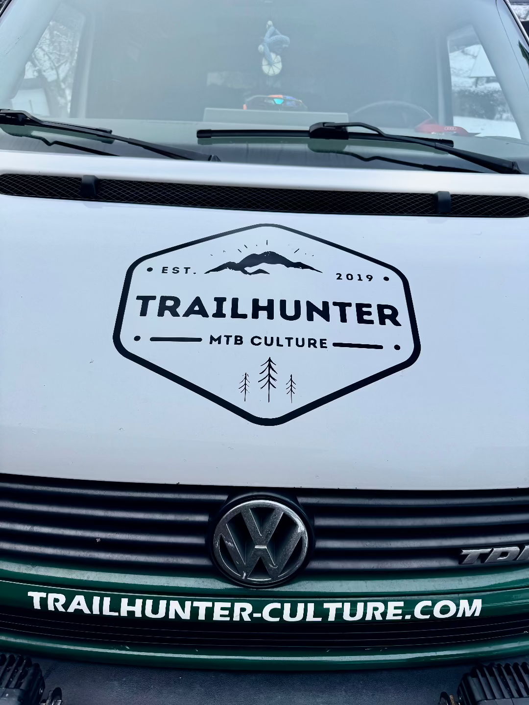 Trailhunter MTB Culture Badge Aufkleber schwarz auf weißer Motorhaube von einem Camper - Van
